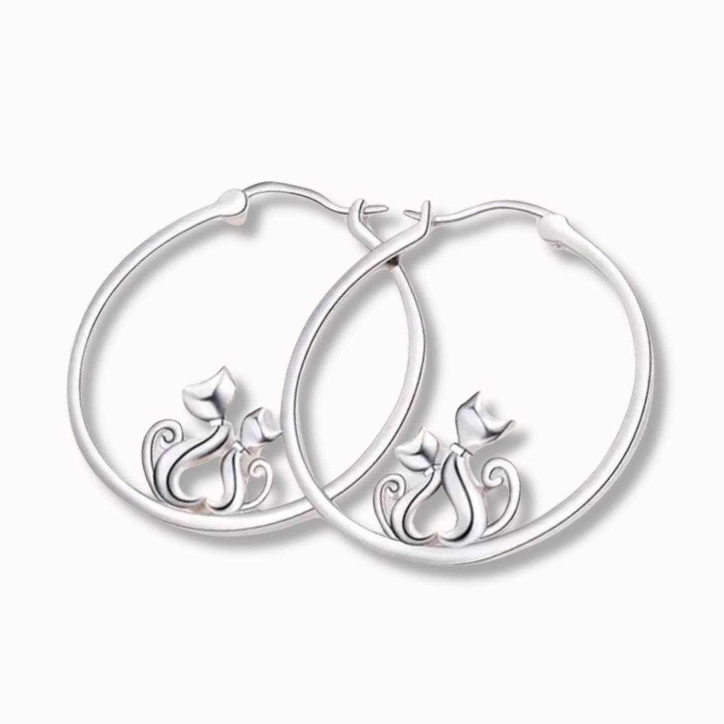 Pendientes de plata con forma de aro con 2 gatos que hacen un corazón con el cuerpo, sobre fondo beige de TOUS