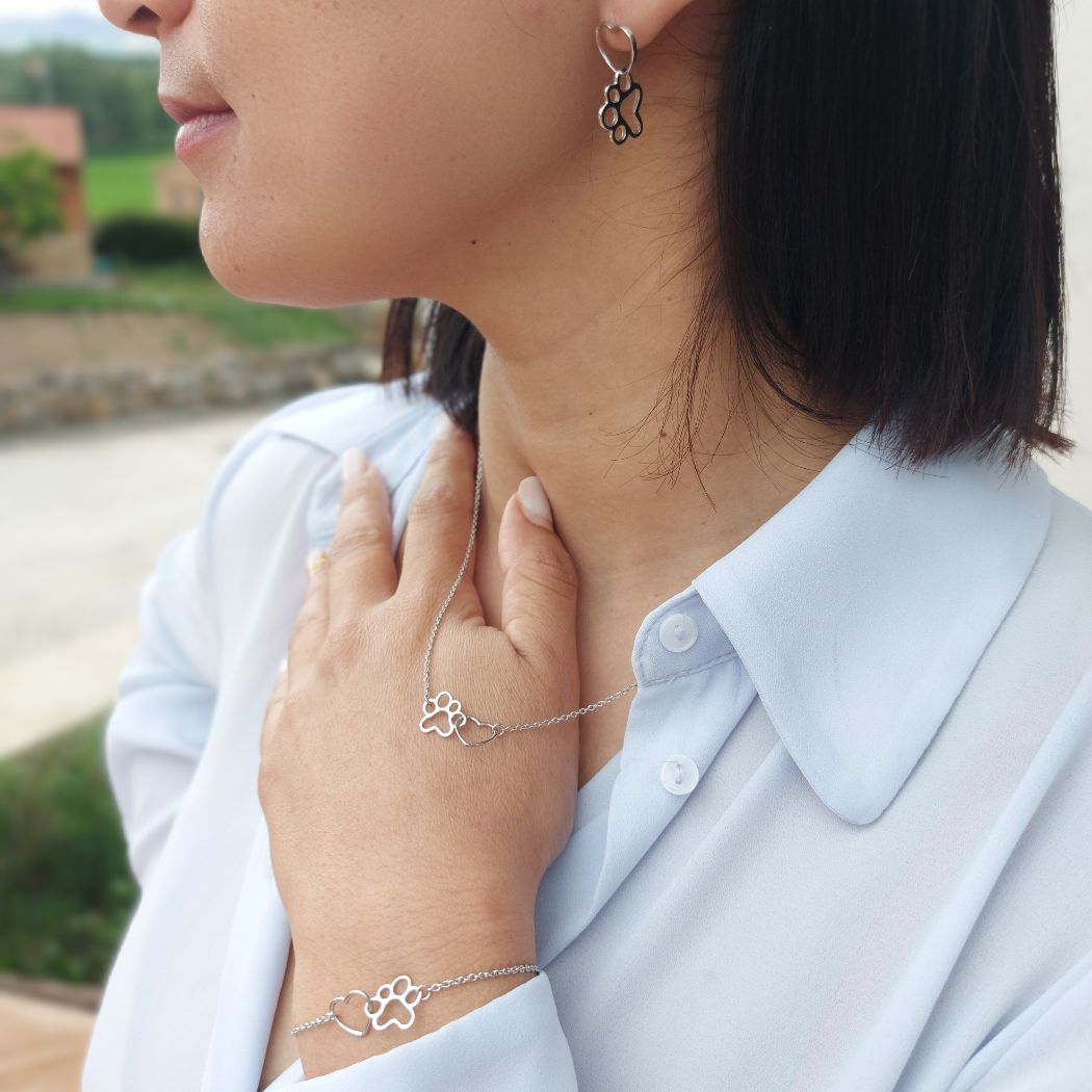 Pack joyas plata mujer corazón y huellitas de perro o gato sobre modelo con camisa azul de TOUS