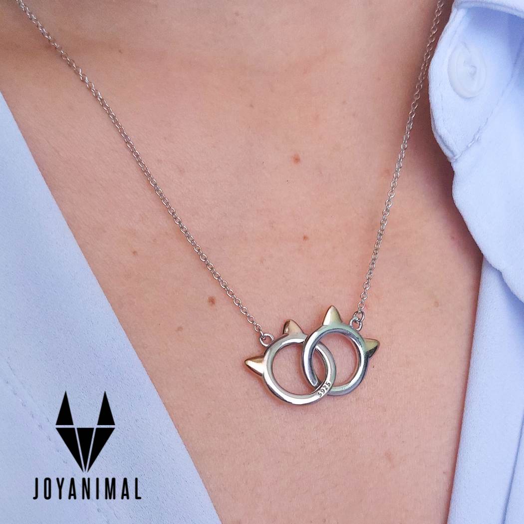 Collar de plata con colgante de dos gatitos entrelazados sobre piel de modelo de el corte inglés