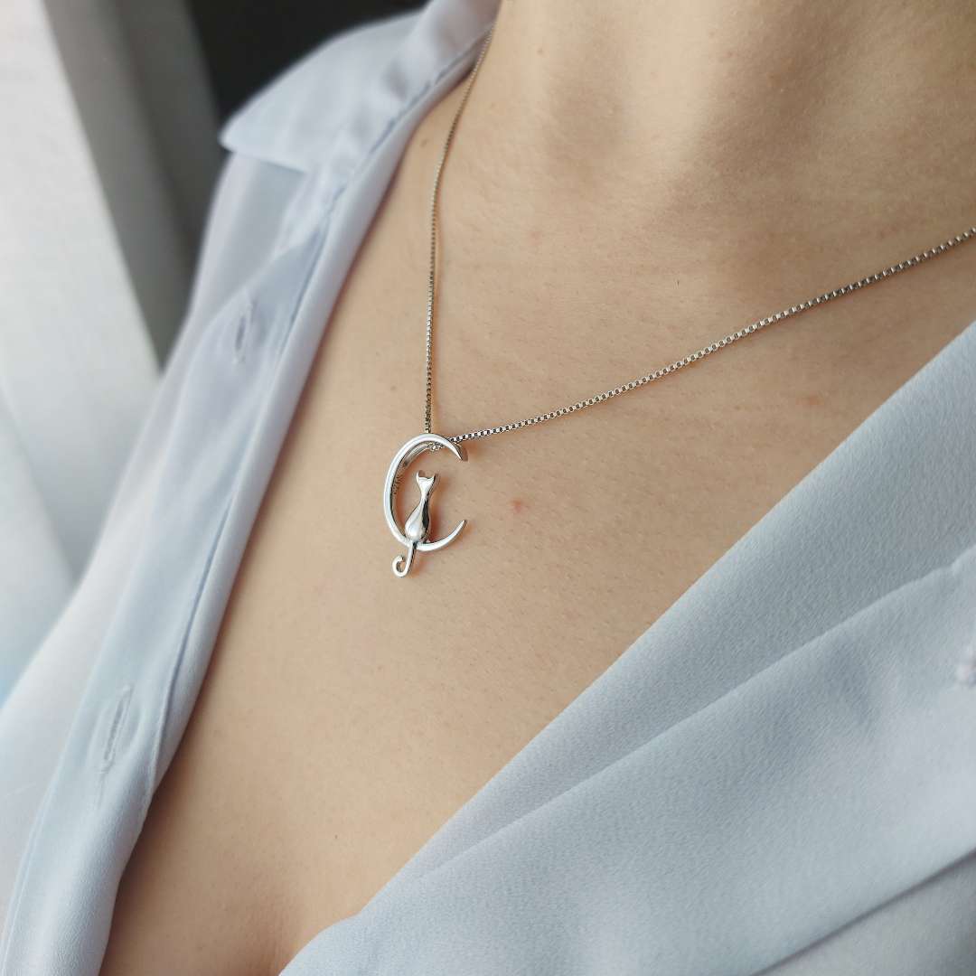 Collar de plata con cadena fina en el escote de una mujer con camisa azul de le petite marie