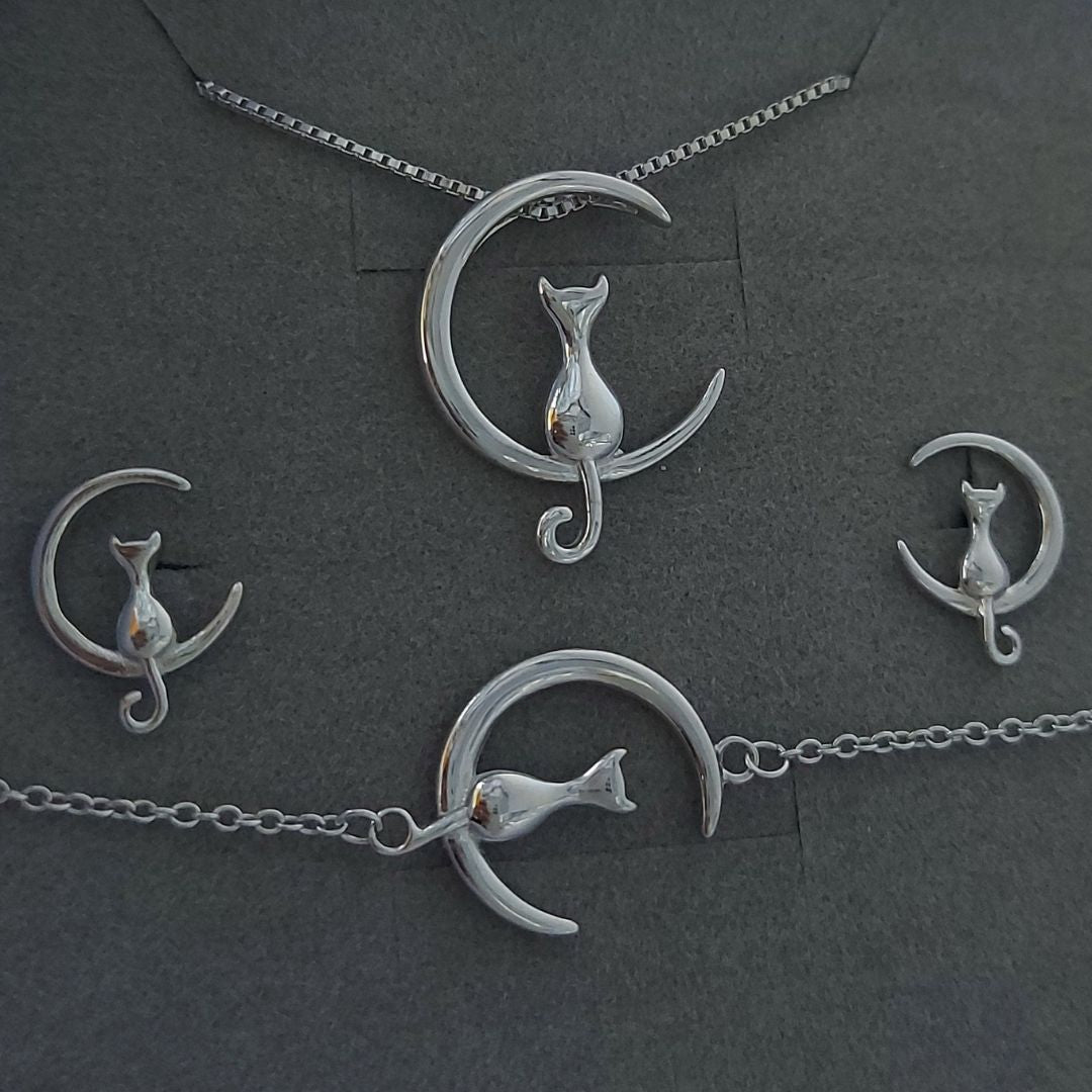 Joyas con gato y luna de plata expuestas en un cojinete de color gris del corte inglés
