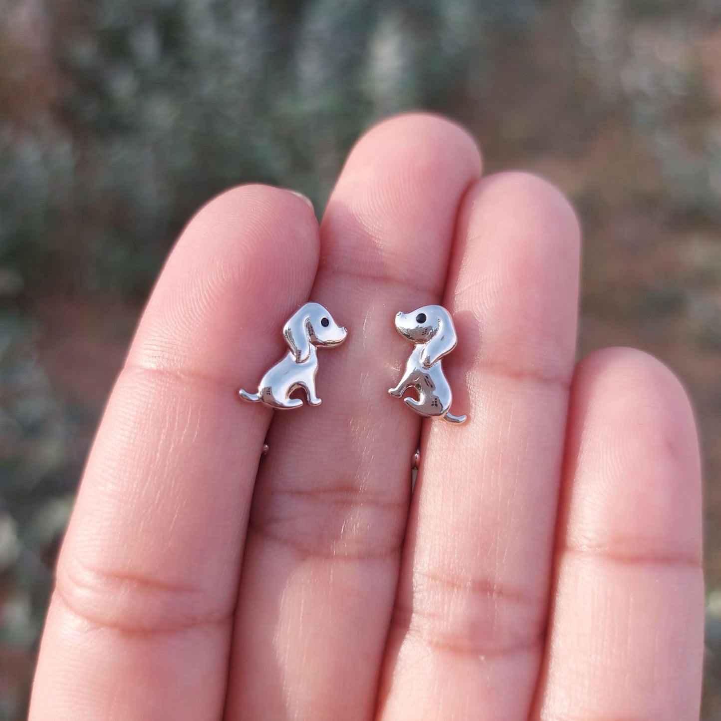 Pendientes de perrito de plata sobre mano de mujer de PANDORA