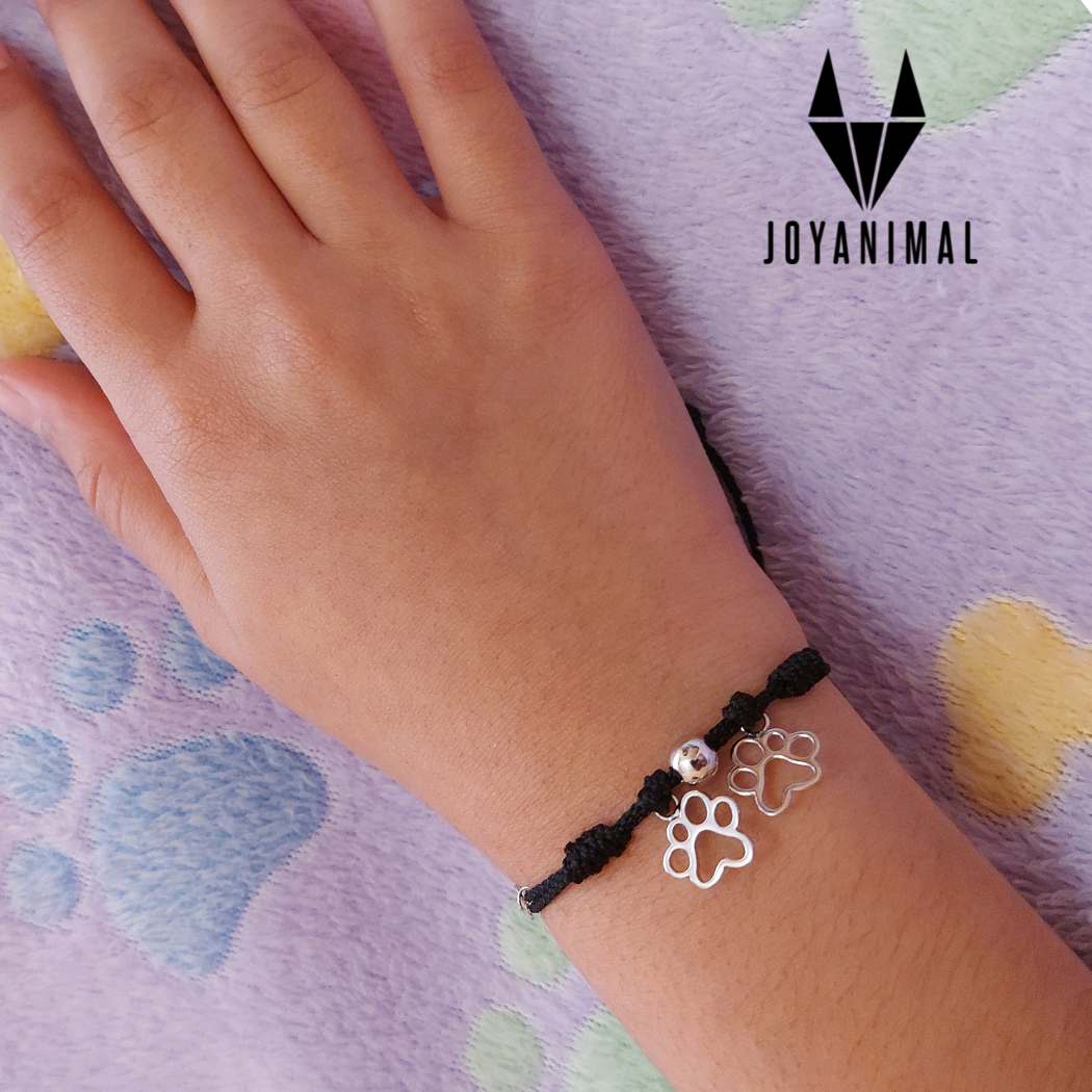 Pulsera de hilo ajustable, con dos huellas de plata, en mano de adolescente PANDORA