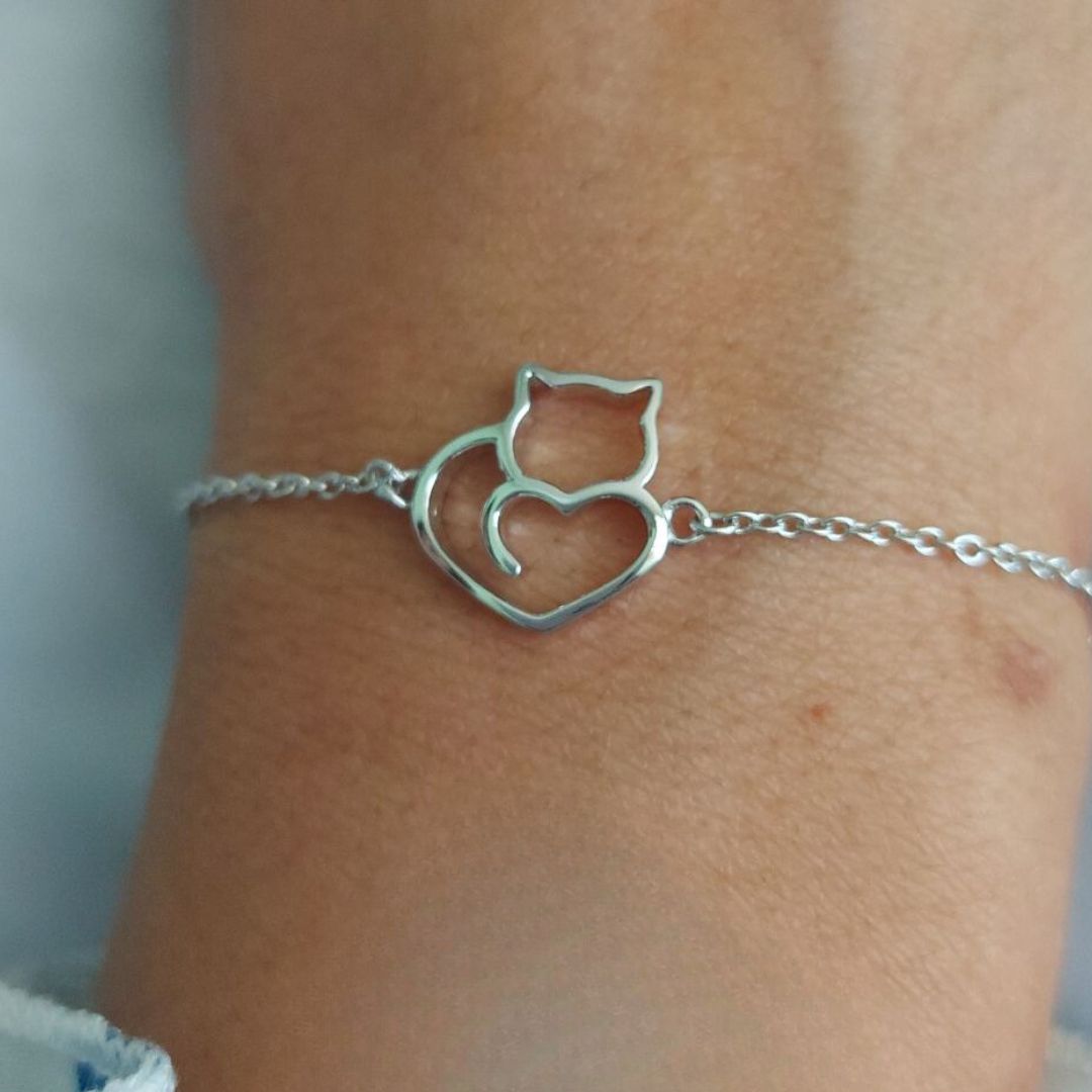 Pulsera con la silueta de un gato formando un corazón de plata, puesto en una muñeca de mujer de PANDORA