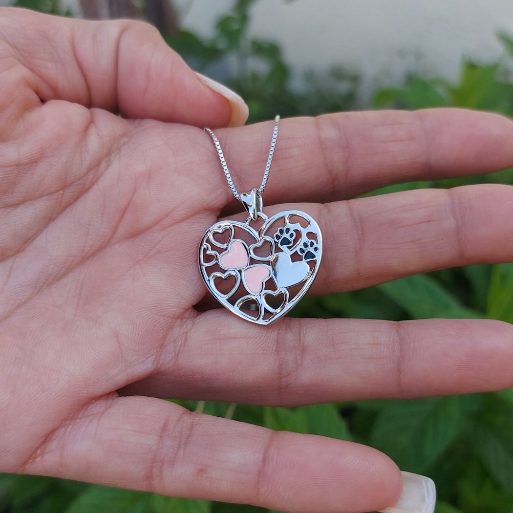 Colgante de árbol de vida con corazones rosas y huellas de perros y gatos puesta sobre mano de modelo TOUS