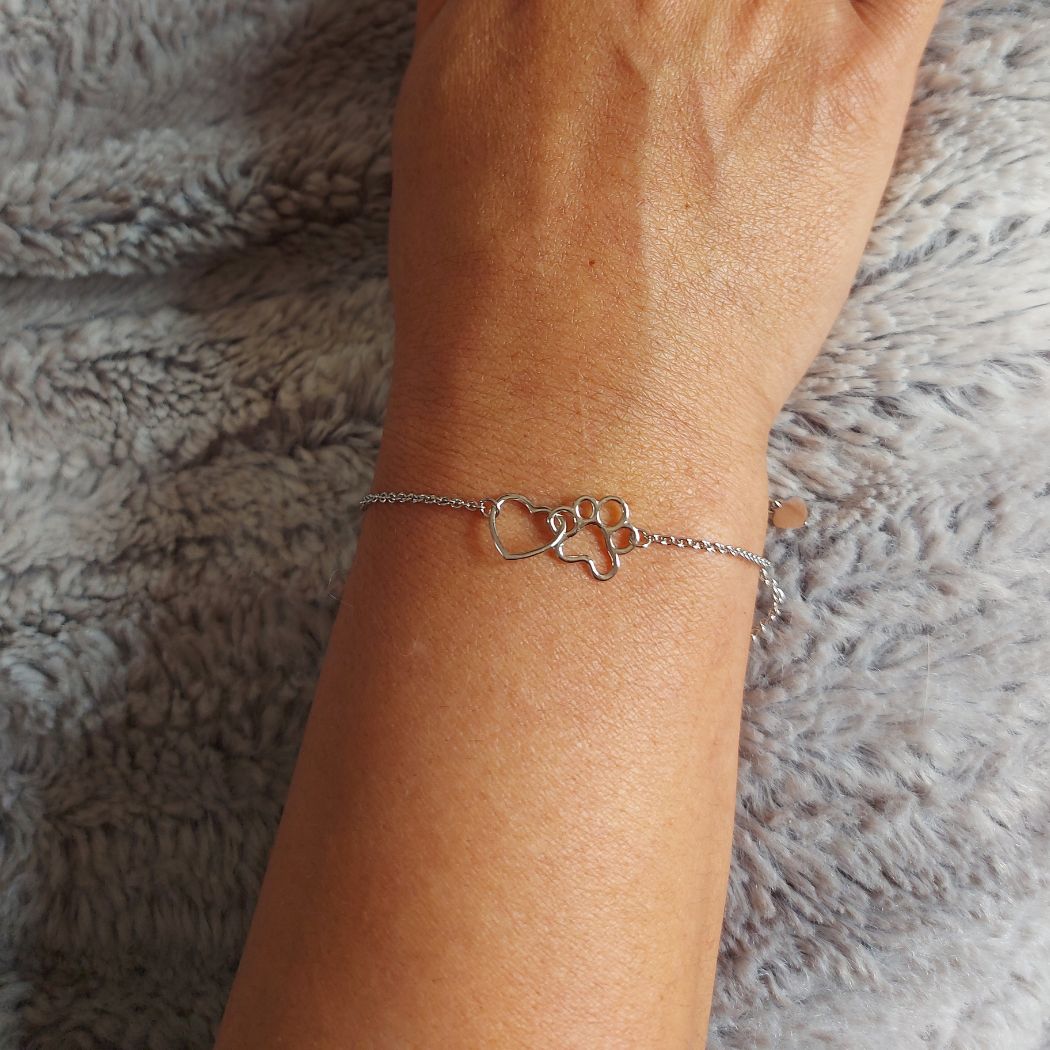Pulsera de plata con huella y corazón de sobre manta gris de TOUS