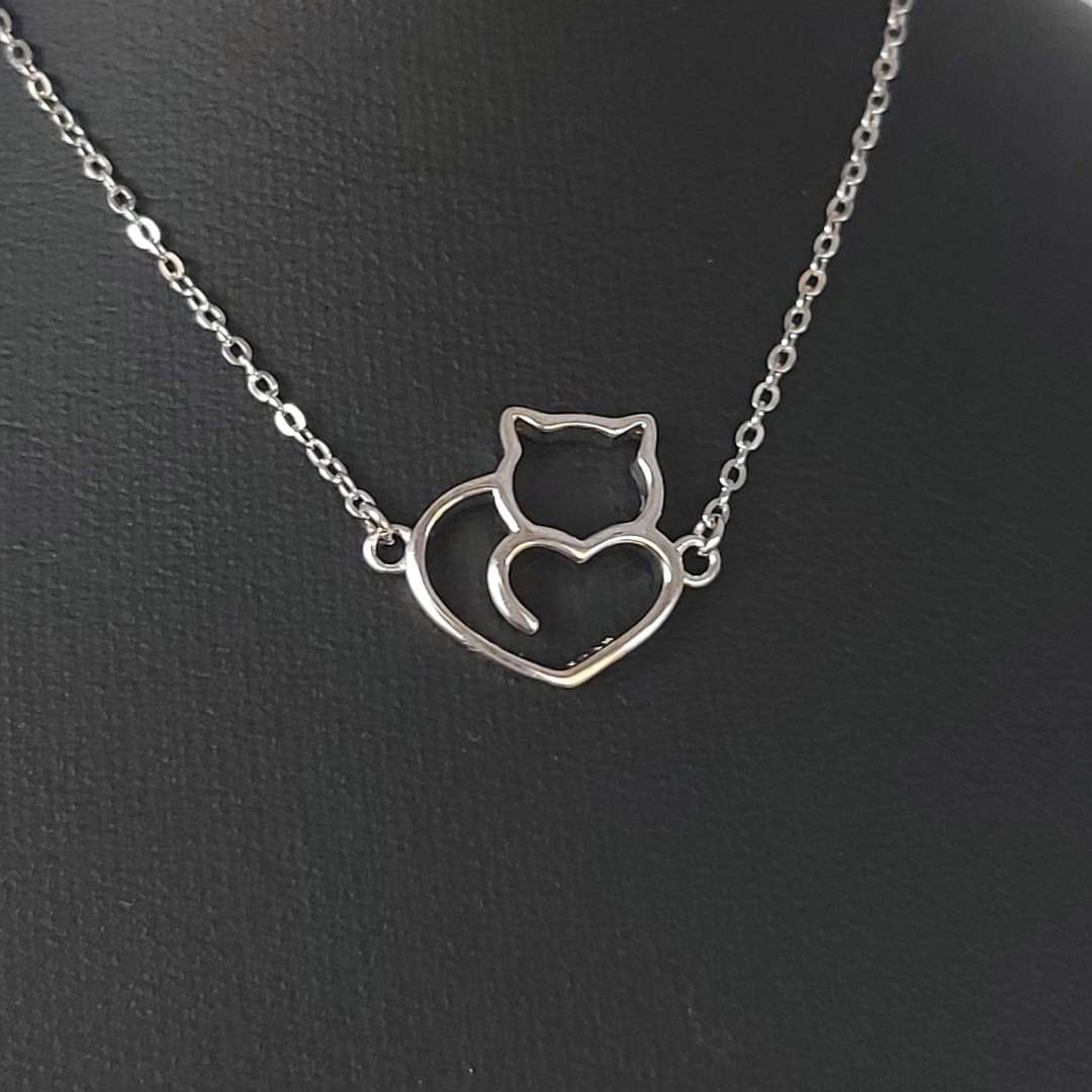 Collar de plata con forma de un corazón con un gato de TOUS sobre fondo negro