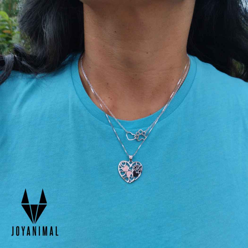 Gargantilla de plata con colgante de árbol vida y huellas y corazones conjuntados, sobre mujer modelo con camiseta azul de el corte inglés