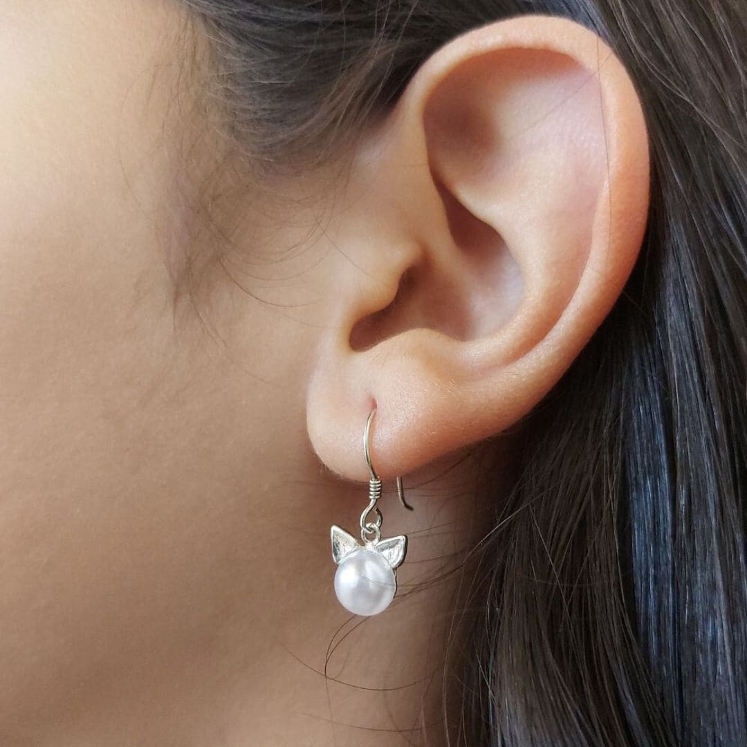 Pendientes que cuelgan con una perla y orejas de gatito de Pandora en oreja de modelo