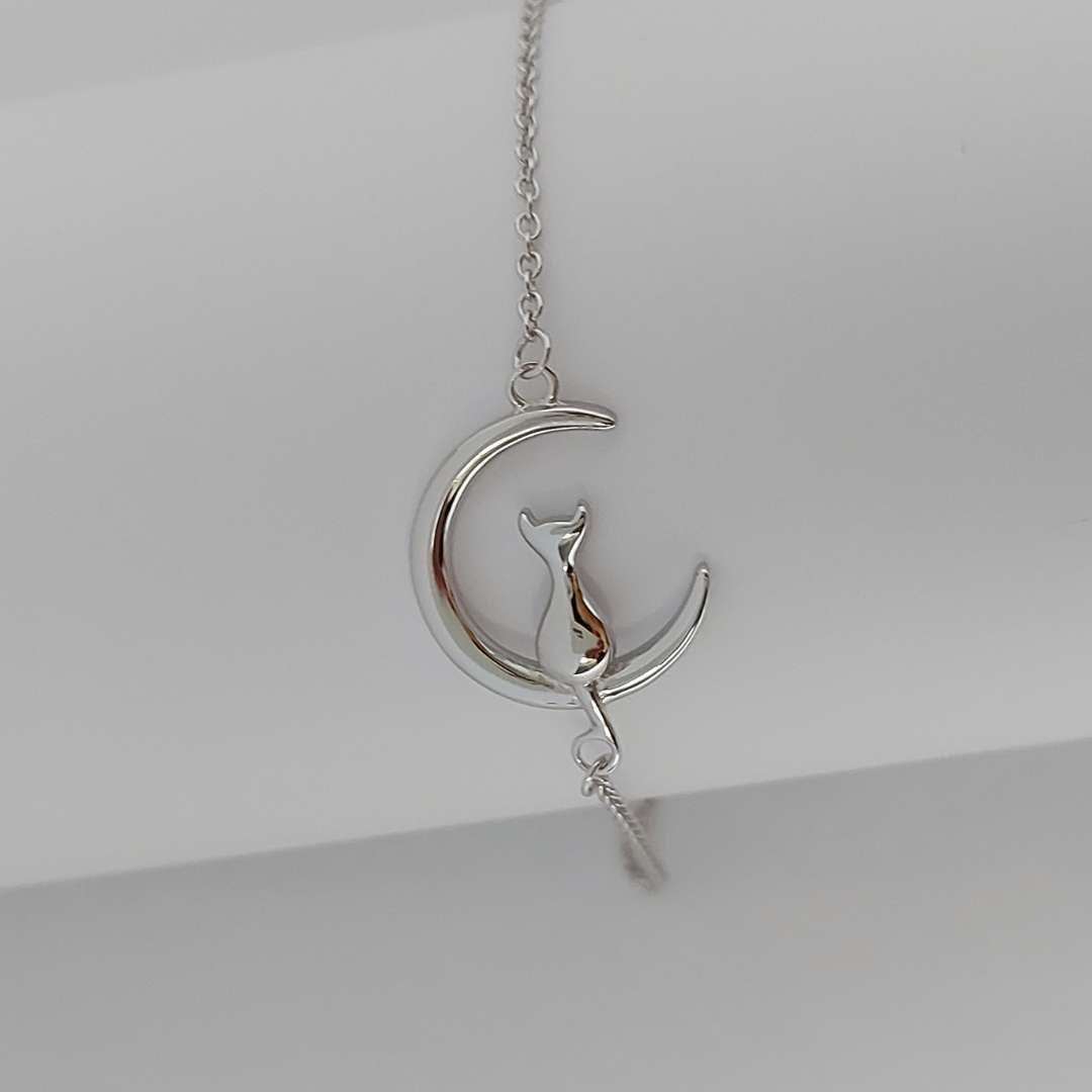 Pulsera de plata con un gato sentado en la luna, sobre fondo blanco de PANDORA