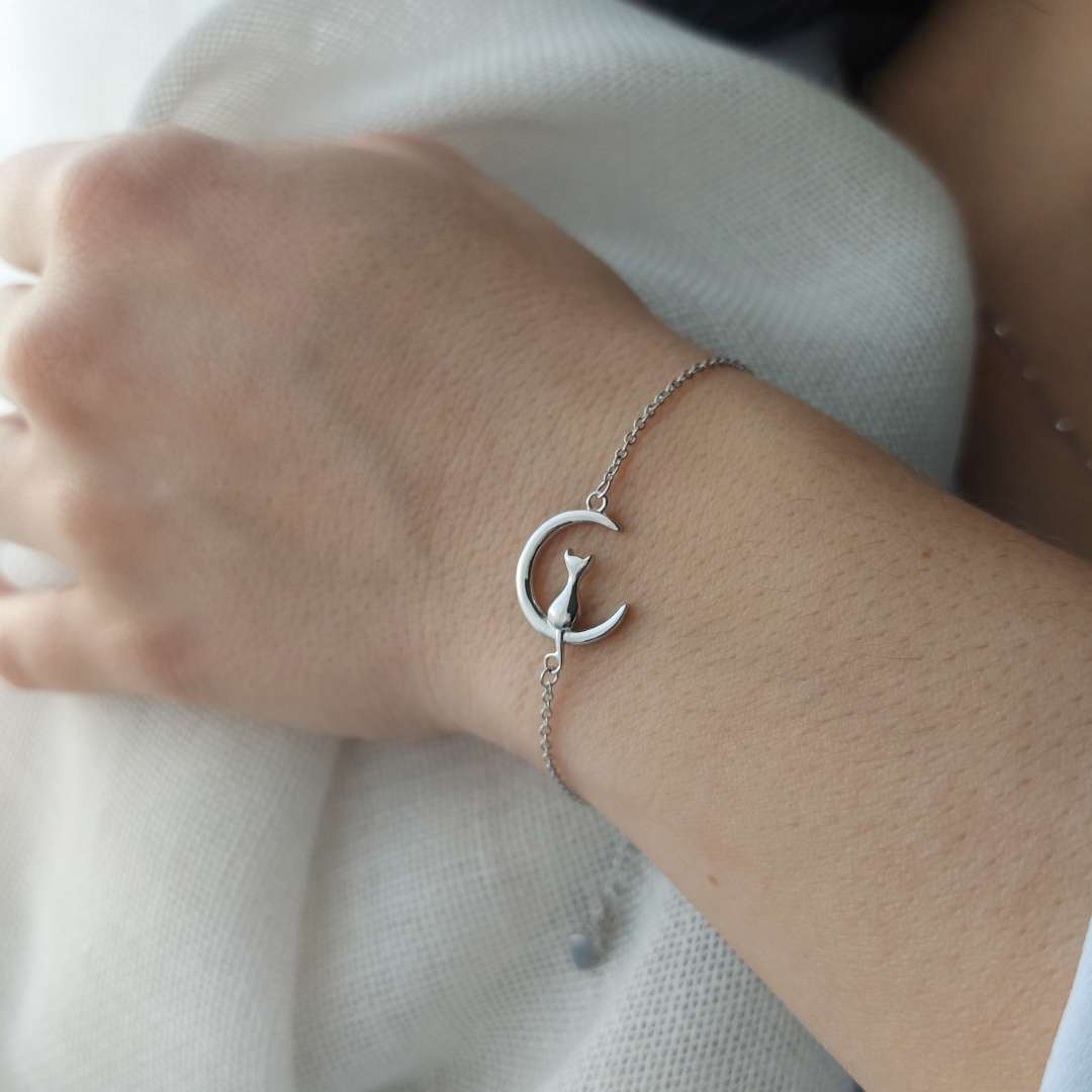 Pulsera con un gato sentado en la luna puesto sobre la muñeca de una modelo de pandora