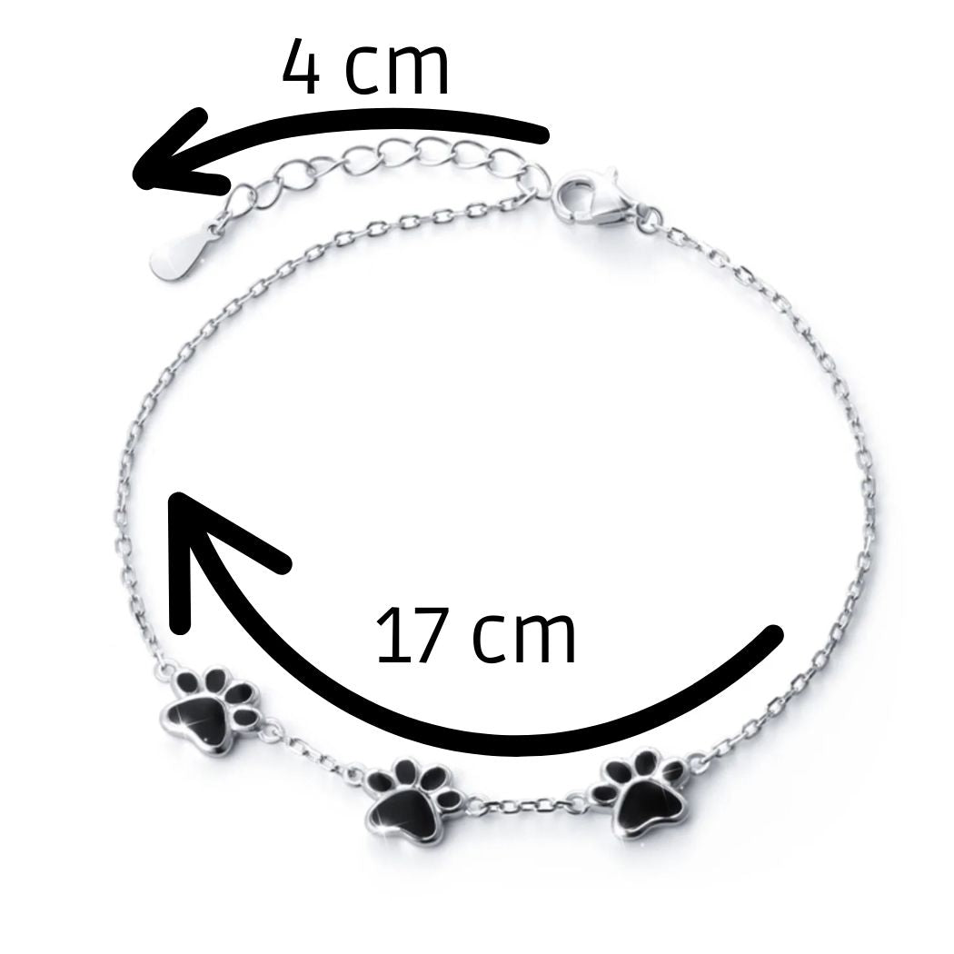 Infografía de la pulsera con huellitas negras de perrito o gatito, con las medidas: 17 ctm de cadena + 4 de extensión.