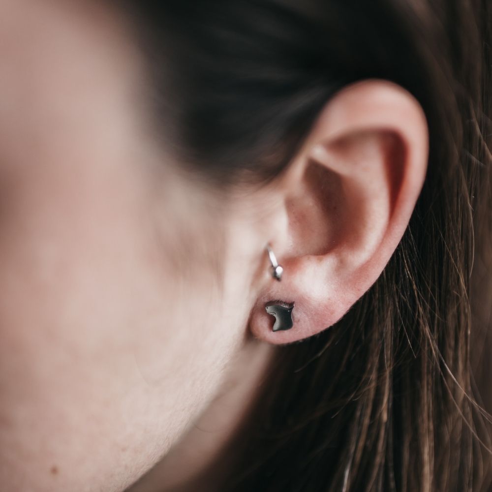 Pendiente pequeñito en la oreja de una modelo, usado como segundo pendiente junto a un arete de singularu