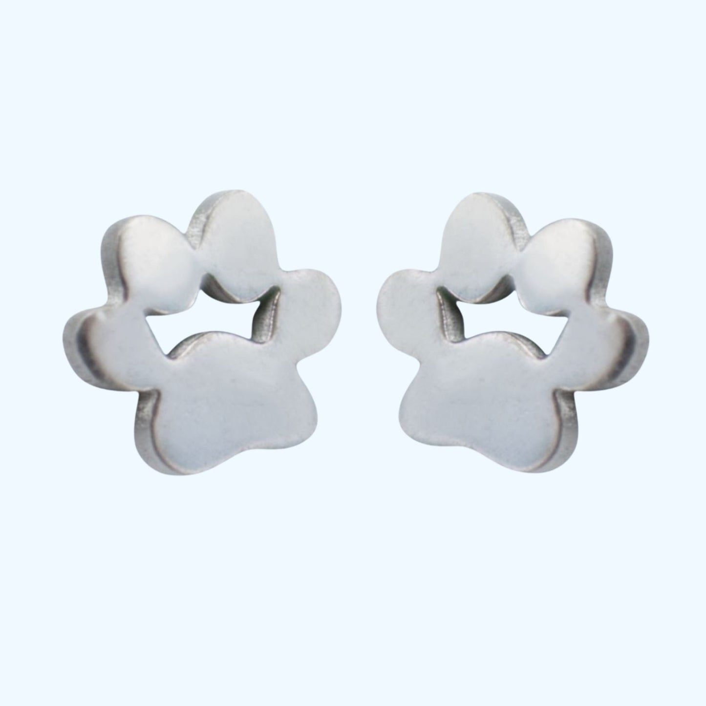 Pendientes con forma de huellas de perrito o gatito en acero quirúrgico sobre fondo azul de tous