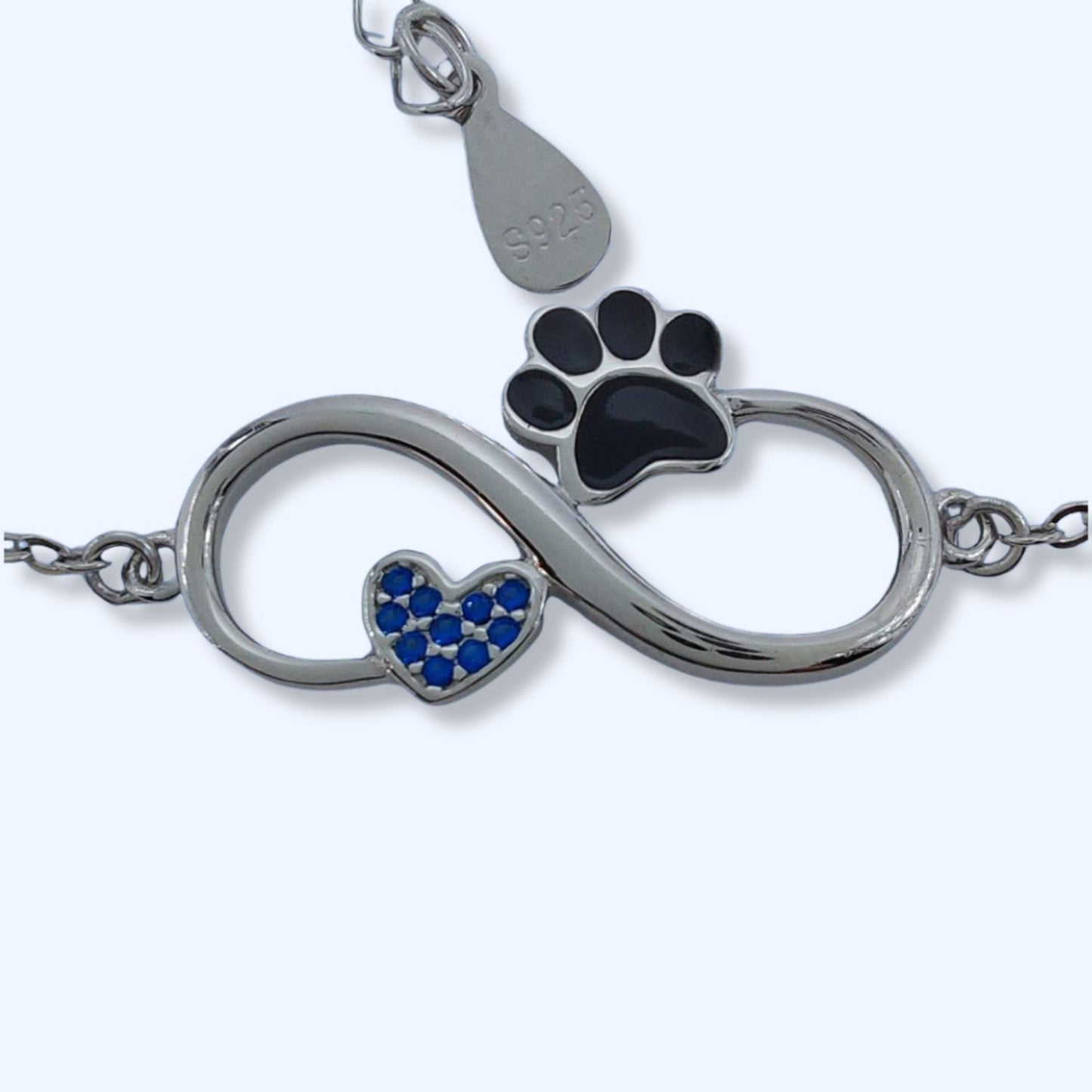 Pulsera con símbolo del infinito con un corazón y una pata de peludo, junto al mini colgante de plata S925, la pulsera simboliza el amor infinito a nuestros perros o gatos, sobre fondo azul de pandora