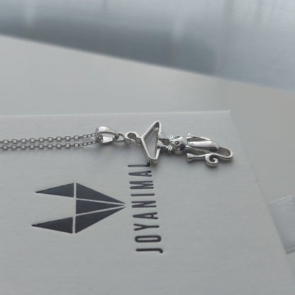 Collar con colgante de gato colgando de una percha de plata de ley, sobre caja de regalo con logo de JOYANIMAL