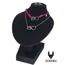 Pendientes y collar de plata con huellas de perros o gatos y corazones con pulsera de hilo rosa a juego, expuesta en el corte ingles en busto negro.