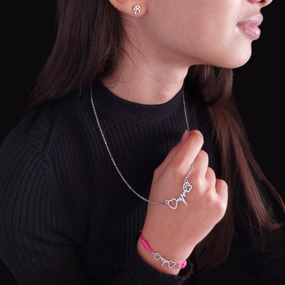 Niña modelando con pendiente con huellita de plata, collar de acero con colgante de huella de perro o gato con latido y corazón y una pulsera ajustable con el mismo diseño mascotero en hilo rosa de el corte inglés