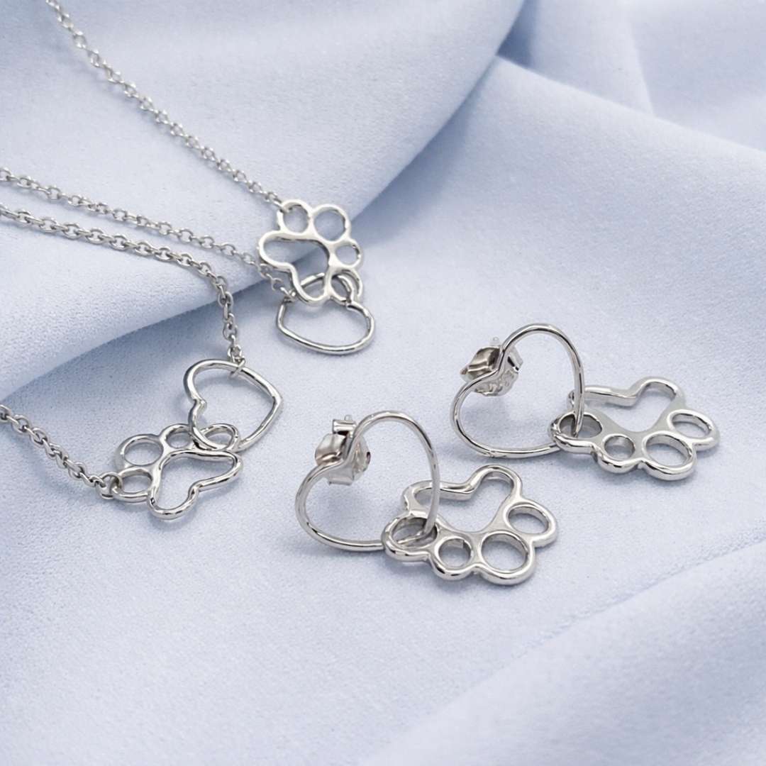 Pack joyas plata mujer corazón y huellitas de perro o gato sobre tela azul de TOUS