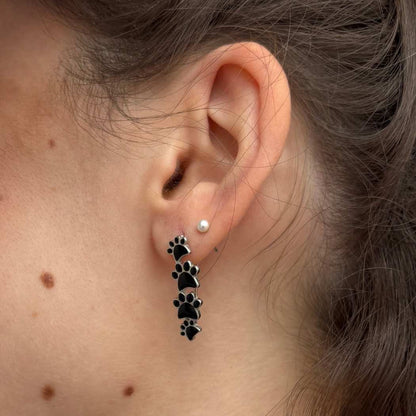 Pendientes colgantes de plata con cuatro huellas negras.