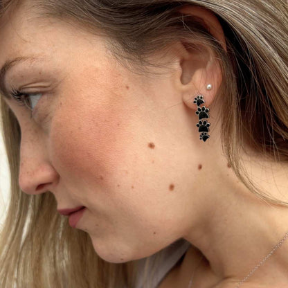 Pendientes colgantes de plata con cuatro huellas negras.