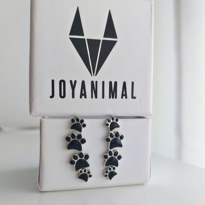 Pendientes colgantes de plata con cuatro huellas negras.