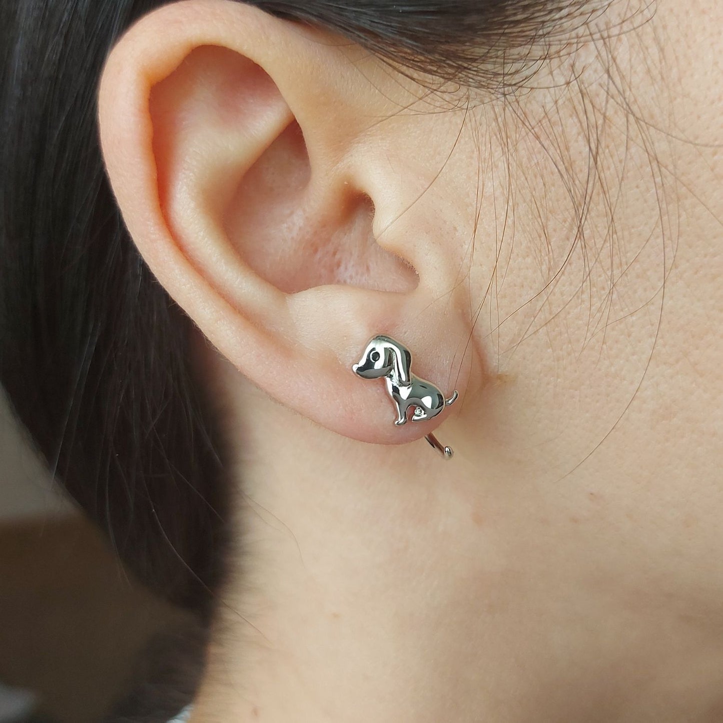 Pendiente pequeño de perrito PANDORA sobre oreja de modelo mujer