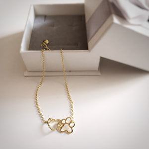 Pulsera de plata con forma de corazón y huella  bañada en oro sobresaliendo de una bonita caja de regalo del corte inglés.