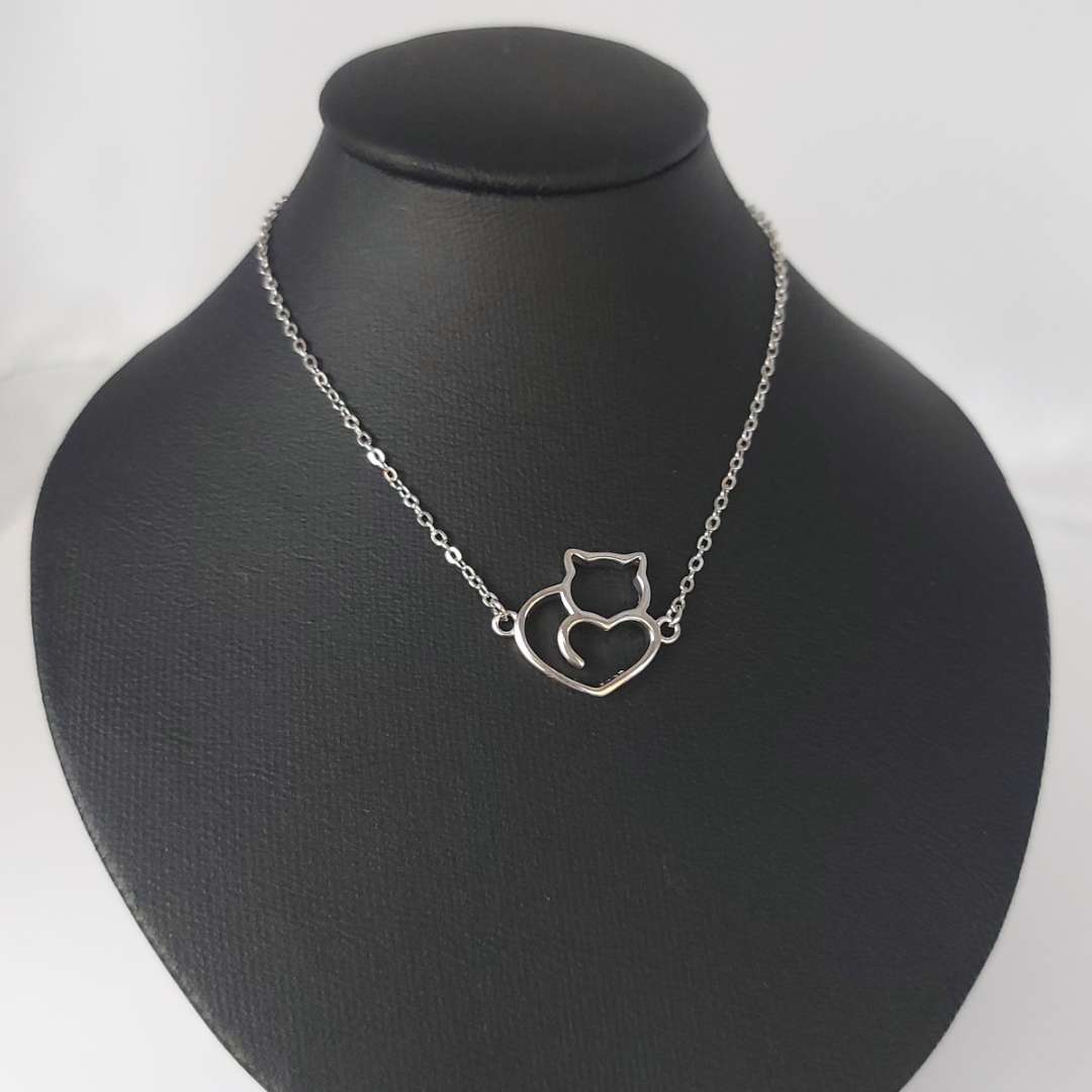 Collar de plata con colgante de gatito y corazón sobre un maniquí negro lepetitmarie