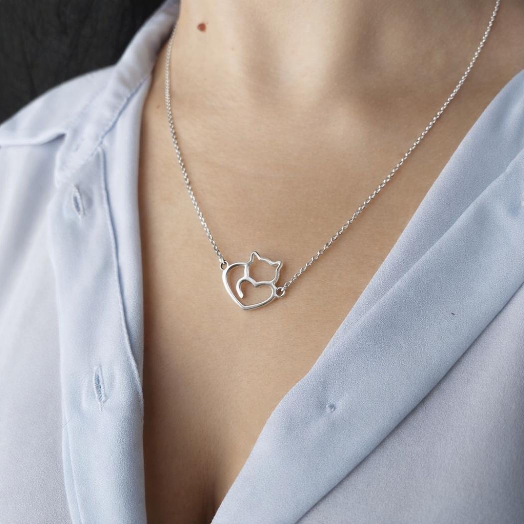 Collar de plata con un gato y un corazón en el escote de una modelo con camisa azul del corte inglés