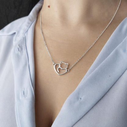 Collar de plata con un gato y un corazón en el escote de una modelo con camisa azul del corte inglés