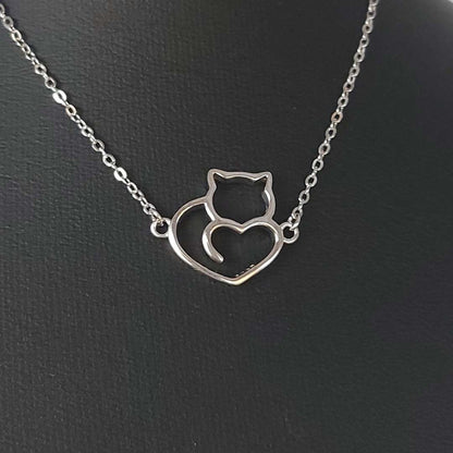 Collar de plata con forma de un corazón con un gato de TOUS  sobre fondo negro 