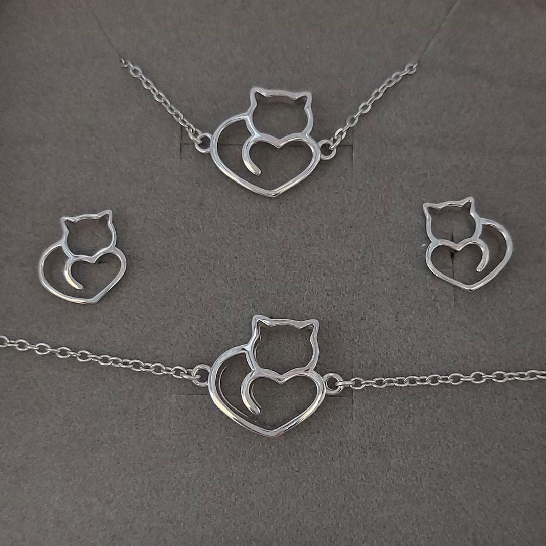 Collar, pulsera y pendientes de plata con forma de gatitos y corazones sobre fondo gris del corte inglés