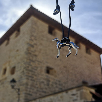 Pulsera hilo ajustable negra con galgo de plata con una torre de fondo