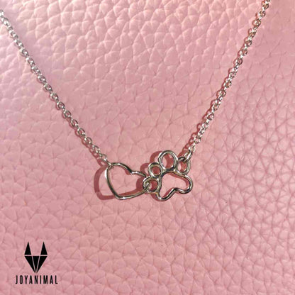 Collar con una huella y un corazón de plata de ley by Pandora, sobre una tela rosa