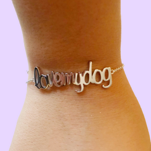 Pulsera de plata sobre la muñeca de una mujer con la palabra de love muy dog (amo a mi perro) Pandora